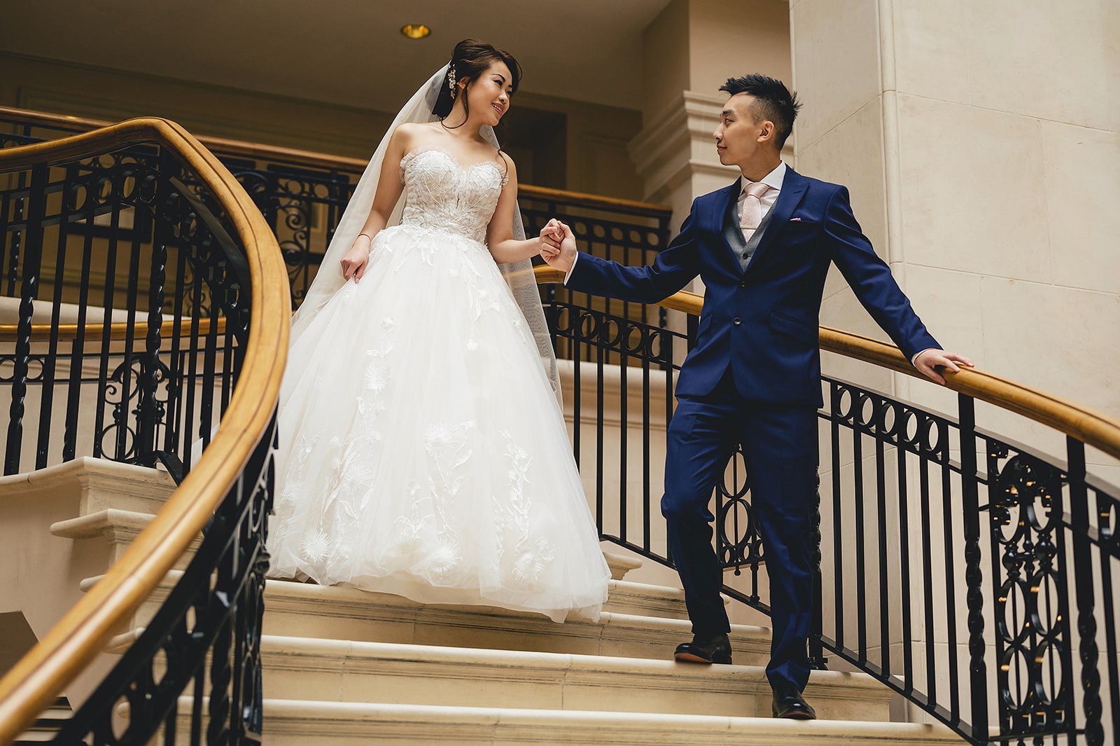 A couple holding hands on a grand staircase