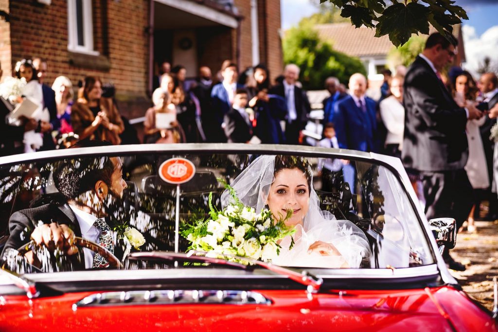 bride and groom in red convertible